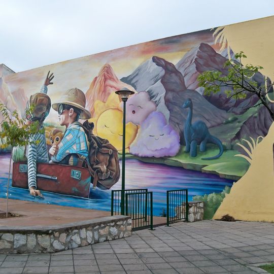 Mural que presentan dos niños navegando en una maleta sobre las aguas de una laguna prehistórica imaginaria.
