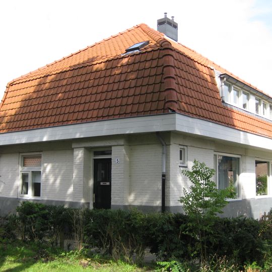 Woning met stijlelementen in de Amsterdamse School, gebouwd met voor die tijd nieuw systeem met betonblokken