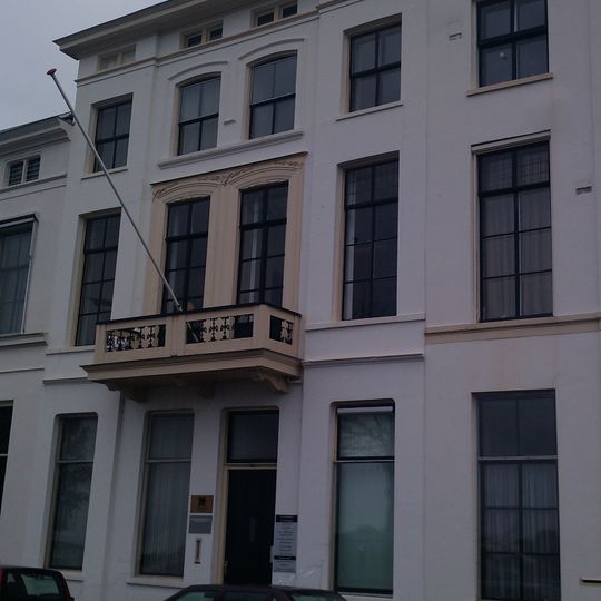 Statig herenhuis met schilddak en gepleisterde lijstgevel met stucwerk en balcon