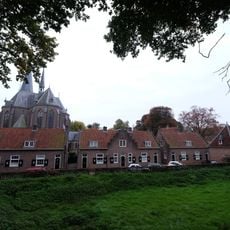 Symmetrisch opgebouwd centraal woonblok, bestaande uit drie aaneengesloten eengezinswoningen, waarvan de middenwoning eindigt in een trapgevel