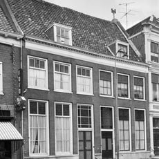 Gedeelte van in oorsprong twee huizen onder een hoog zadeldak tussen puntgevels. De lijstgevel die voor het pand werd opgetrokken heeft een hardstenen plint.