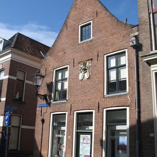 Hoekhuis met door rollaag afgedekte topgevel en met geprofileerde natuurstenen dekplaten