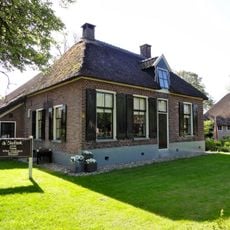 Boerderij onder rieten dak met dwars gebouwd woondeel en bedrijfsdeel met houten wanden