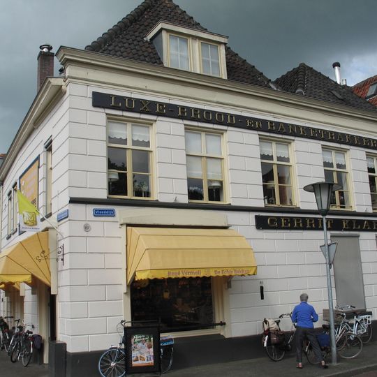 Hoekpand met in blokken gepleisterde lijstgevel op plint en vensters in empire-stijl