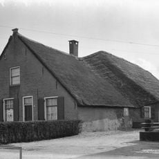 Boerderij met schilderachtig rieten zadeldak, dat zowel het woonhuis als de hogere stal overdekt. Puntgevel met vlechtingen en vensters met luiken en twintig- en zestienruitsroedenverdeling.