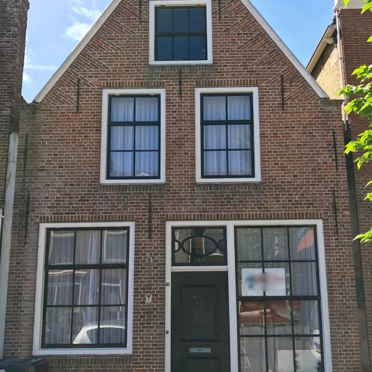 Pand met deur met kussenpanelen onder zadeldak tegen puntgevel