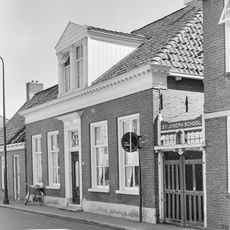 Vijf traveeën breed woonhuis met omlijste ingang, zesruitsvensters en geblokte kroonlijst onder schilddak met dakkapel met pilasters