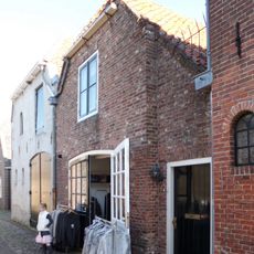 Woonhuis met afgewolfd schilddak en gepleisterde gevel onder rechte lijst