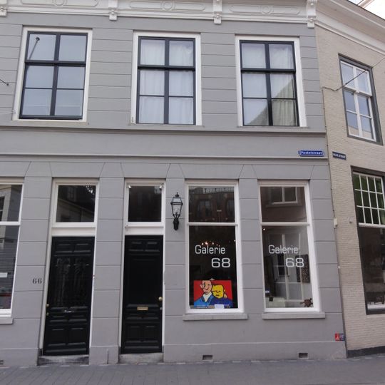 Huis met gebosseerd gepleisterde gevel met kroonlijst op consoles die voortzetting is van die van nr 66