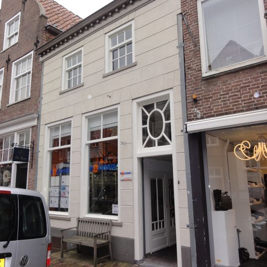 Huis met gebosseerd witgepleisterde lijstgevel, kroonlijst op klossen en schilddak