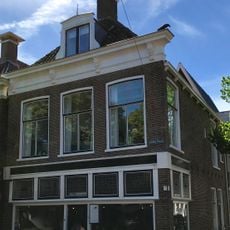 Hoekpand met herbouwde voorgevel met rechte kroonlijst onder schilddak met topschoorsteen met bord