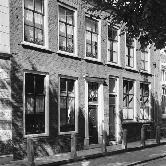 Pand met lijstgevel aan de straat, voordeuromlijsting met bovenlicht en verdiepte panelen in de zijposten, 6-ruits schuifvensters met rode strekken en rode beneden rollaag.