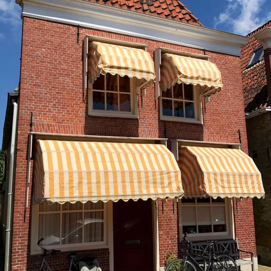 Pand met verhoogde rechtafgesloten gevel met negenruitsvensters onder zadeldak