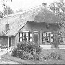 Boerderij onder hoog, rieten wolfsdak, dat uitsteekt boven de voorgevel