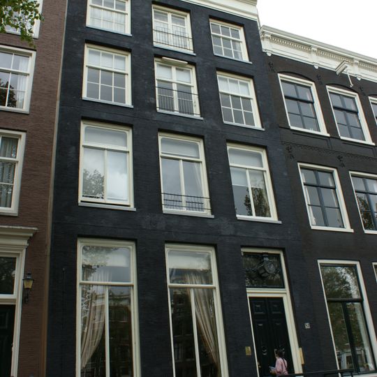 Pand met gevel onder rechte stenen lijst en gebeeldhouwde attiek, met gebeeldhouwde stoep en deurpartij