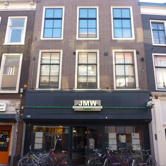 Pand met rijzige bakstenen gevel, hijsbalkluik in rechte kroonlijst, onderpui gewijzigd