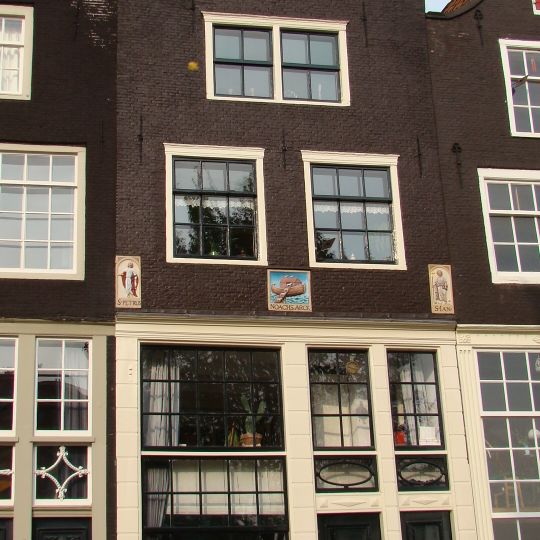 Huis, houten pui, waarboven gevel onder klokvormige top . Twee oeils-de-boeuf, drie gevelstenen