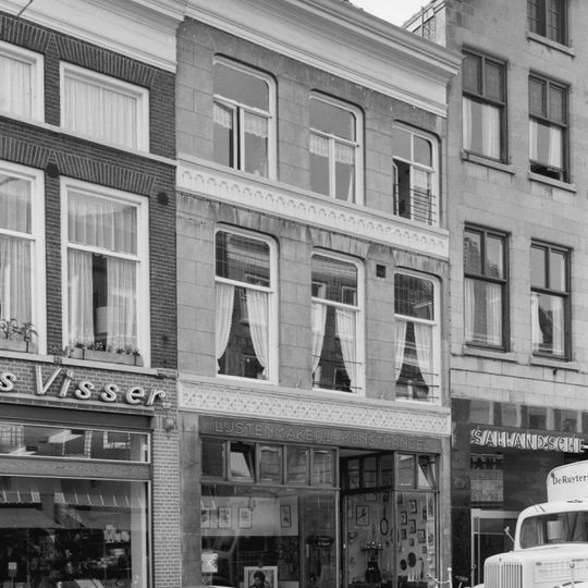 Pand met jongere winkelpui in gepleisterde lijstgevel met vroeg neogotisch fries