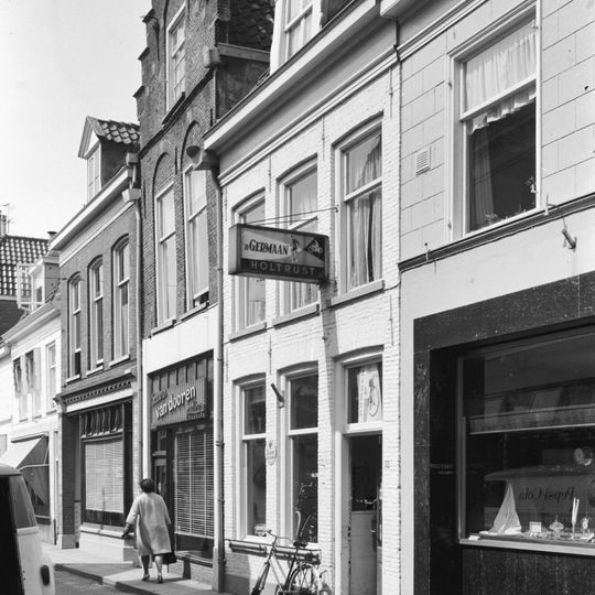 Huis met door toppilaster op kraagsteen bekroonde trapgevel en jongere winkelpui