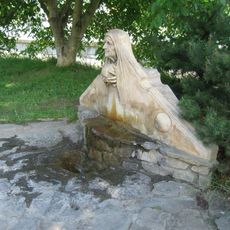 Plastika nad pramenem kyselky ve středu obce