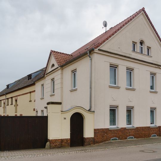 Wohnhaus, daran angebautes Seitengebäude, Toranlage und Hofpflaster eines Bauernhofes Dorfstraße 36