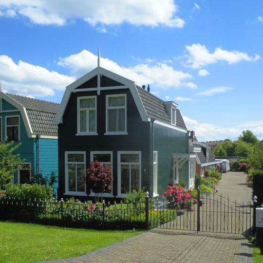 Houten huis met zolderverdieping onder mansarde kap met verbindingsbalk tussen de boeiborden en makelaar; T-vensters