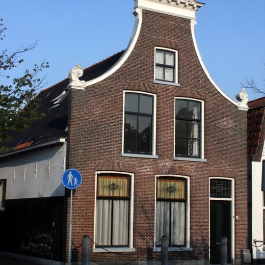 Pand onder zadeldak tegen door fronton bekroonde klokgevel