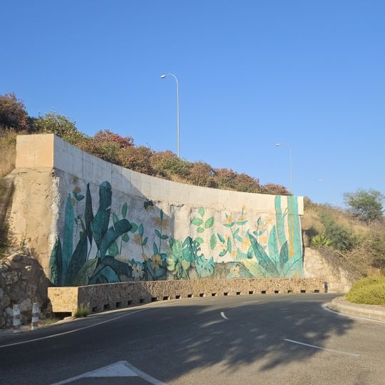 El mural representa sobre fondo blanco un paisaje vegetal, con hojas de helechos, plantas trepadoras, flores amarillas y una mariposa.