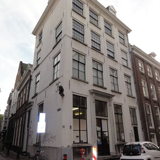 Rijzig hoekpand van begane-grond, drie verdiepingen en schilddak met dakkapellen.