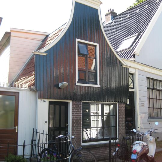 Houten huis met halsgevel en bakstenen onderpui