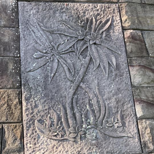 Relief in the stone retaining wall depicting flowers.