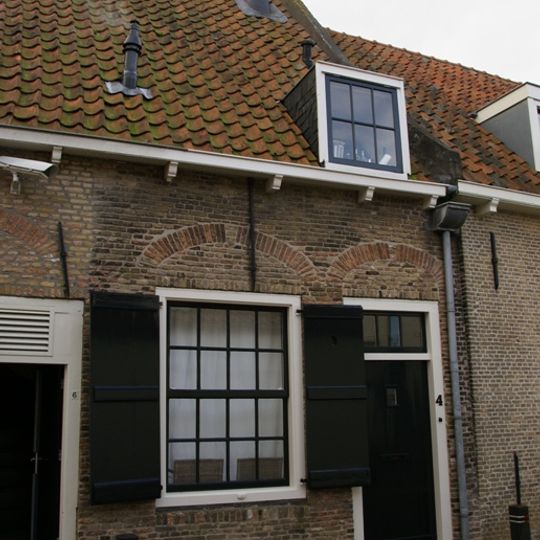 Eenvoudig woonhuis in gele baksteen onder een gezamenlijk dwars met pannen belegd zadeldak met de nrs 6,8 en 10