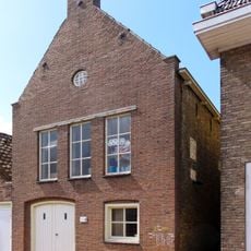 Pand met verdieping met zesruitsvensters en met gootlijst op houten consoles onder met pannen gedekt schilddak