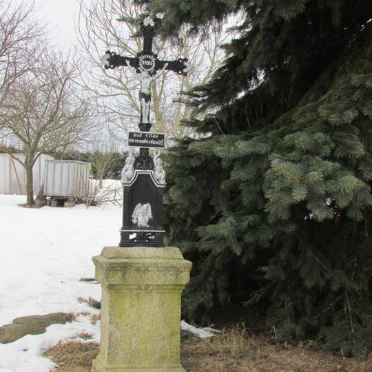 Kříž v západní části Janovic v zahradě domu čp.18
