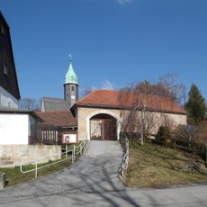 Sachgesamtheit Dorfkirche und Kirchhof Langenwolmsdorf, mit folgenden Einzeldenkmalen: Kirche mit Einfriedung, Torhaus und Kriegerdenkmal für die Gefallenen des Ersten Weltkrieges (siehe dazu auch Einzeldenkmalliste Obj. 09289785) sowie Kirchhof (Ga