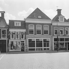 Pand met verdieping onder voor afgeschuind zadeldak met topschoorsteen waarop bord