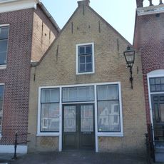 Huis met tuitgevel. Timmermanswerkplaats. Pui met middendeur