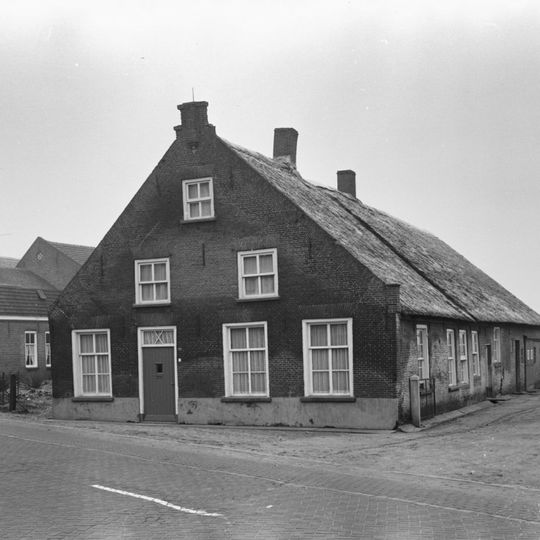 Boerderij van het Langstraatse type, met aan de voorzijde een tuitgevel met trappen en toppilaster; zes- en vierdelige schuiframen. Rieten zadeldak, aan de achterzijde afgewolfd