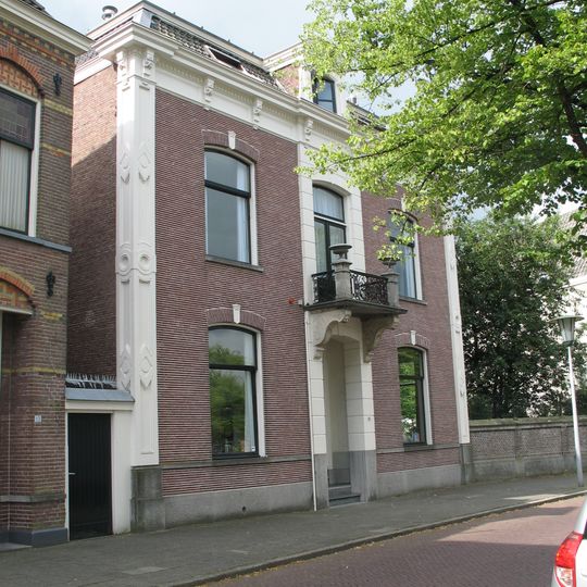 Herenhuis met gepleisterde middenpartij met kroonlijst, door siervazen bekroond balkon op consoles en dakkapel met gebogen fronton