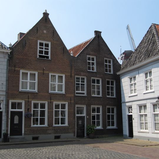 Huis met gebosseerd witgepleisterde lijstgevel en schilddak