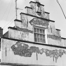 Hoekpand met gepleisterde trapgevel, zandstenen waterlijsten, toppilaster met sieranker en jonger onderpui