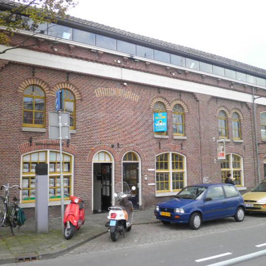 Pakhuis/fabriekspand in sobere eclectische trant uit de tweede helft van de 19de eeuw en naastgelegen kolenloods in art nouveautrant uit 1906, in 1939 samengevoegd tot één bedrijfspand