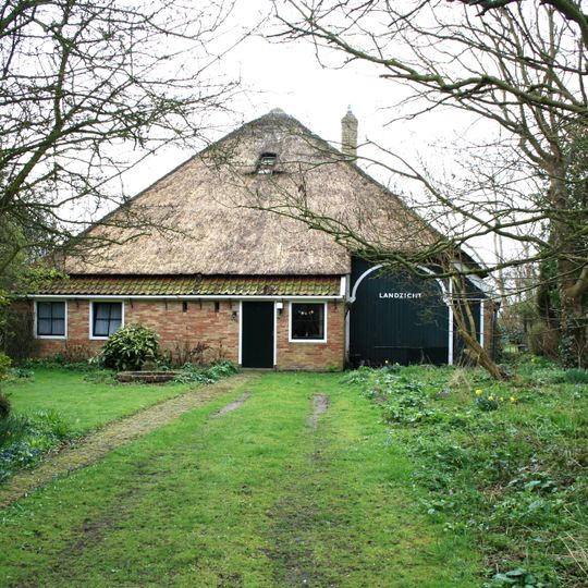 Zuivere stolphoeve met rieten dekking, negenruits vensters en inrit met geschilderde boog