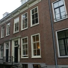Pand voorzien van gevel met kroonlijst op gesneden consoles, deuromlijsting met pilasters