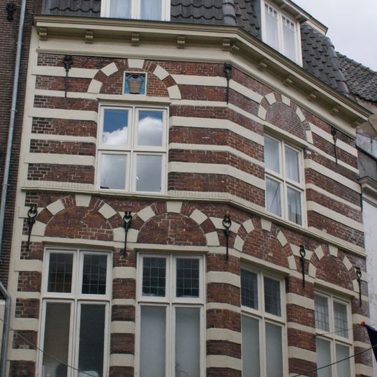 Hoekpand met gevels van bakstenen afgewisseld door zandstenen banden en met sierankers