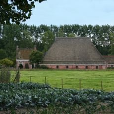 Kop-hals-rompboerderij zadeldak met schoorstenen en borden en met stal onder hoog met pannen belegd schilddak