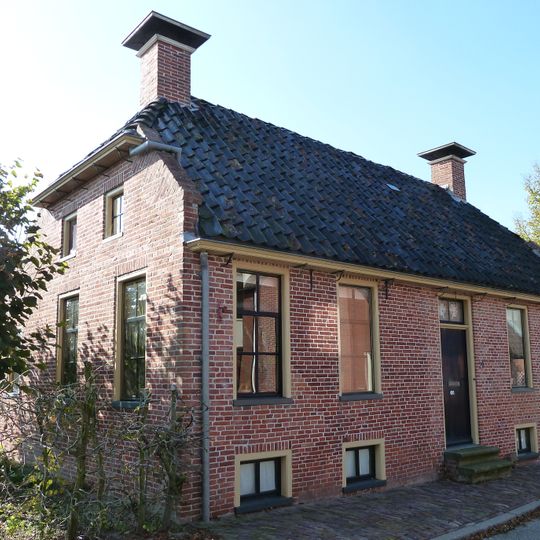 Onderkelderd pand onder zadeldak met wolfseind waarboven schoorstenen