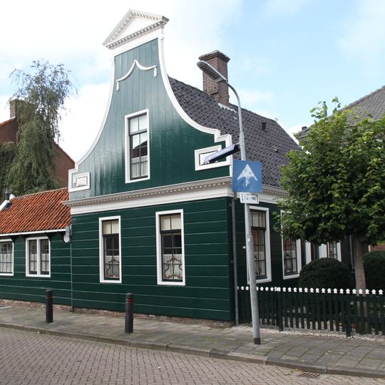 Houten huis met ingezwenkt door fronton bekroond voorschot met zijmeanders
