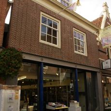 Pand onder diep zadeldak tegen oude achtergevel van puntvorm