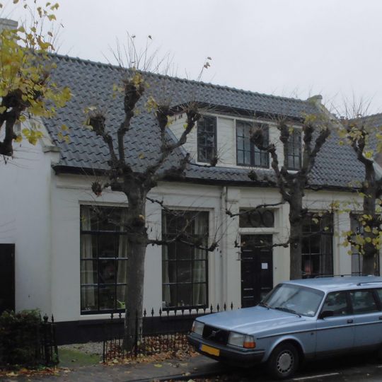Gepleisterde lage woning met lijstgevel, in topgevels eindigend